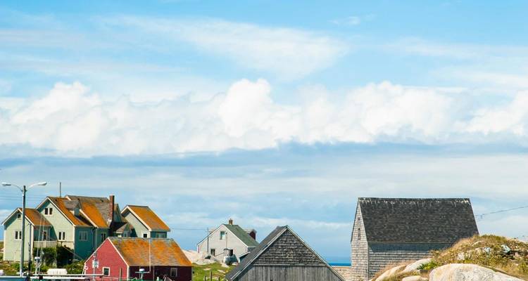 Pintoresco pueblo marítimo con casas de madera coloridas bajo un cielo azul brillante junto al Atlántico.