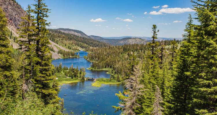 Alpenseenkette umgeben von dichten Nadelwäldern und fernen Bergen unter einem klaren blauen kalifornischen Himmel.