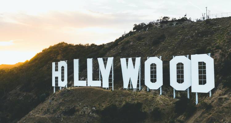Das berühmte weiße Hollywood-Schild steht an einem Berghang, während die Sonne hinter dem Kamm untergeht.