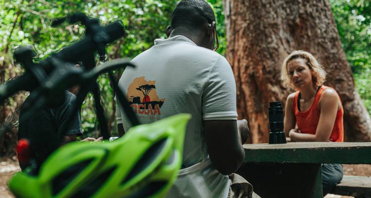 Two people sitting at a picnic table in the forest.