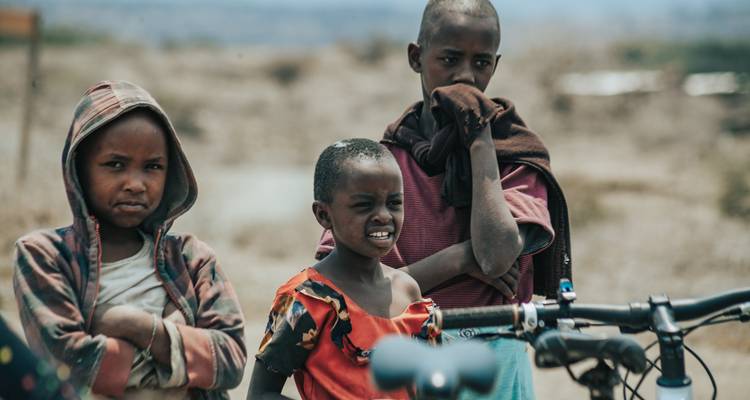 Group of children standing beside bikes in a rural area.