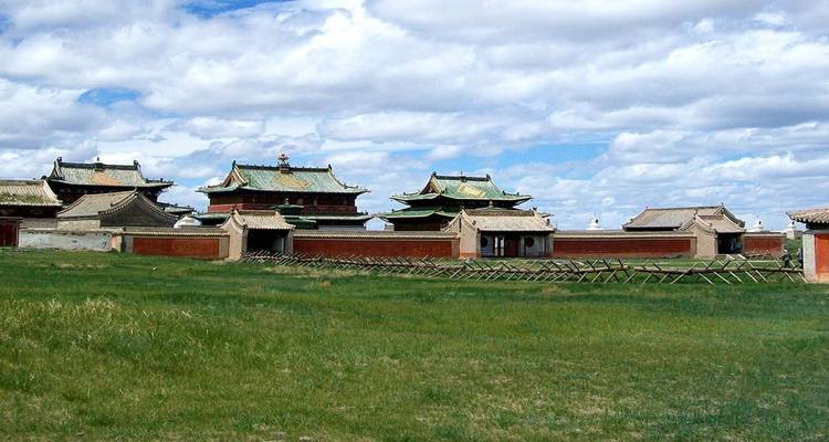 Complex of traditional buildings with green roofs set in a grassy field.