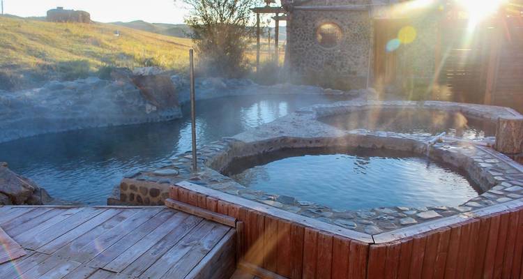 Outdoor hot springs with stone enclosures and surrounding nature.