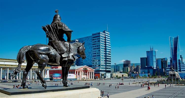 Estatua de un jinete a caballo con un paisaje urbano moderno de fondo.