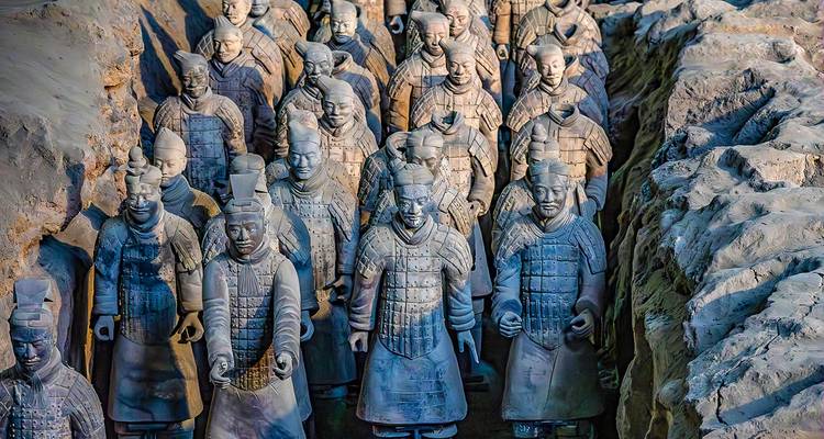 Filas de Guerreros de Terracota a tamaño real se encuentran en trincheras excavadas, con su armadura detallada finamente iluminada.