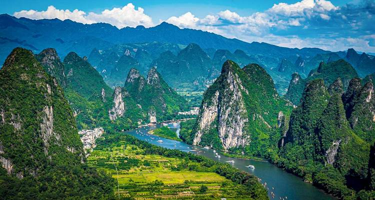 Des pics karstiques spectaculaires encadrent la rivière Li sinueuse avec des bateaux naviguant à travers la campagne luxuriante et verdoyante de Guilin.