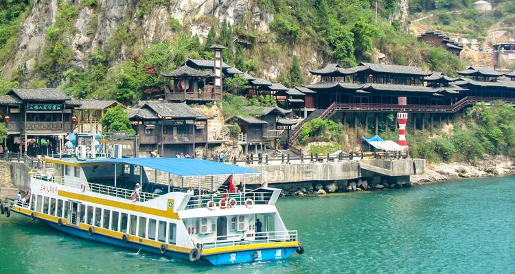 Bateau touristique amarré dans un village pittoresque au bord de la rivière.