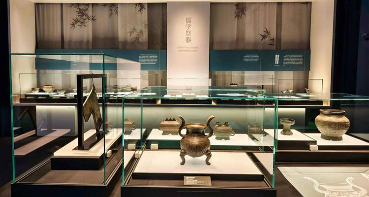 Galerie de musée moderne avec des vases en bronze anciens exposés dans des vitrines.