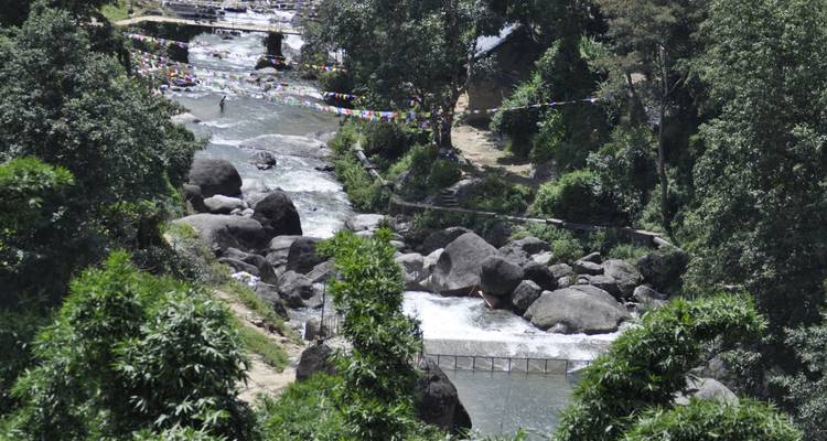 River flowing over rocks with prayer flags above.