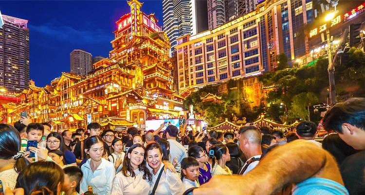 L'atmosphère animée de la nuit aux rues illuminées de la grotte Hongya de Chongqing, bondées de touristes prenant des selfies.