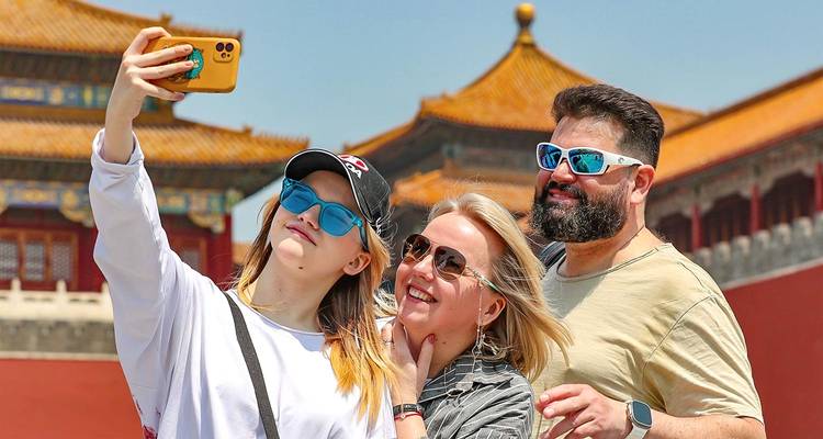 Trois touristes joyeux portant des lunettes de soleil prennent un selfie avec les toits d'un palais historique en arrière-plan