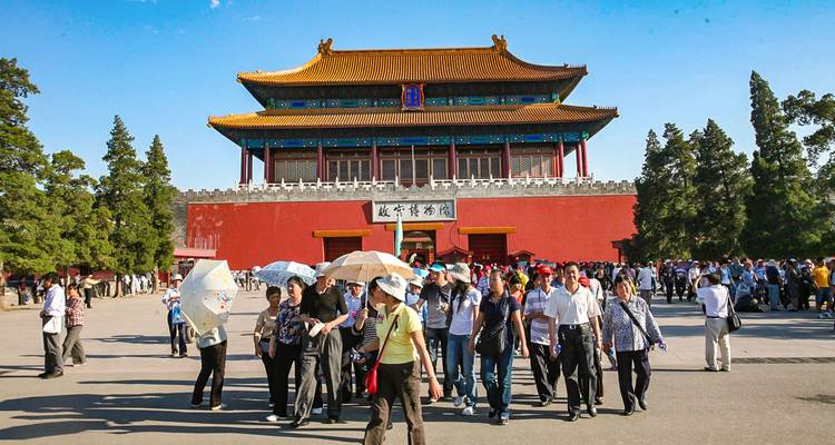 Eine Menschenmenge mit Regenschirmen vor einem historischen chinesischen Gebäude.
