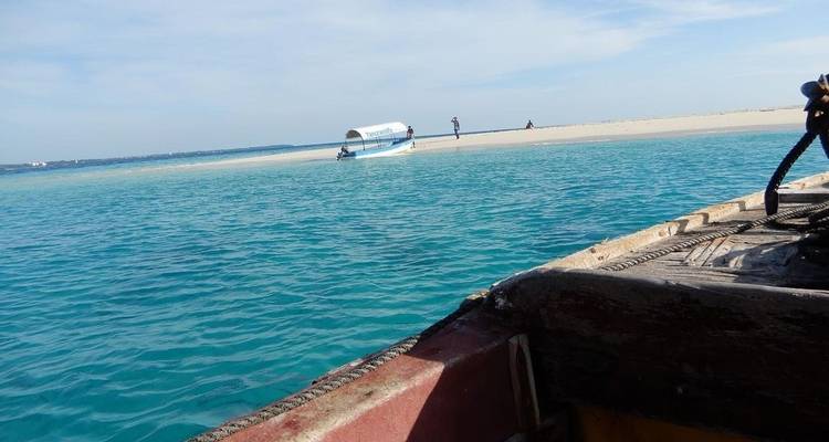 Una hermosa playa con agua azul cristalina y un barco anclado cerca de la orilla.