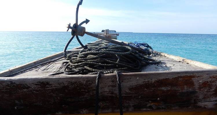 Un barco con un ancla y cuerdas sobre un fondo de agua azul clara.