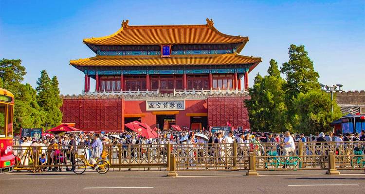 Crowds gather outside the red-walled Tiananmen Gate of the Forbidden City on a bright day.