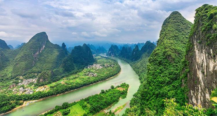 Dramatic aerial of the Li River winding through steep emerald karst peaks and lush farmland.
