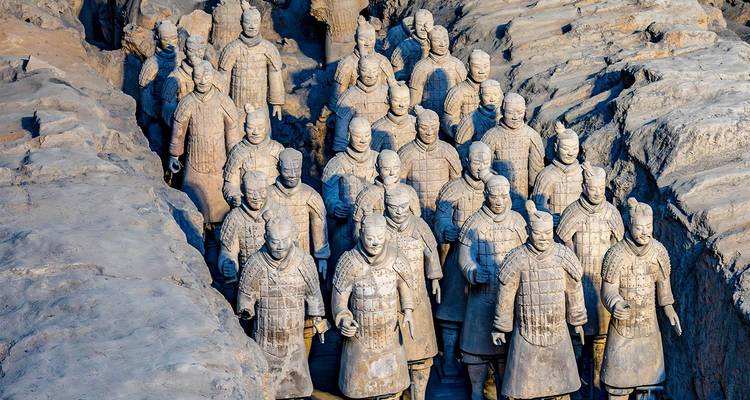 De longues rangées de Guerriers en Terre Cuite excavés se dressant dans des tranchées en terre sous une lumière douce.