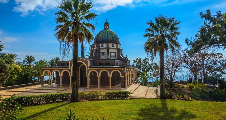 Historische kerk met palmbomen en uitzicht op de kust.