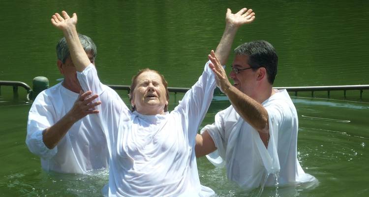 Mensen in witte kledij die deelnemen aan een waterceremonie.
