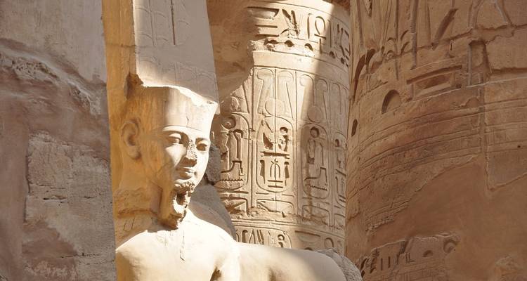 Ancient Egyptian statue and inscriptions in sunlight.