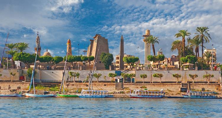 Ribera con obelisco antiguo y palmeras en Egipto.