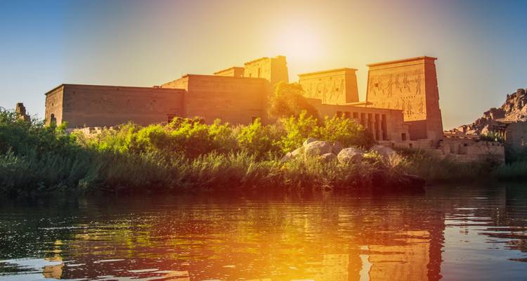 Templo iluminado por una vibrante puesta de sol con reflejos del río.