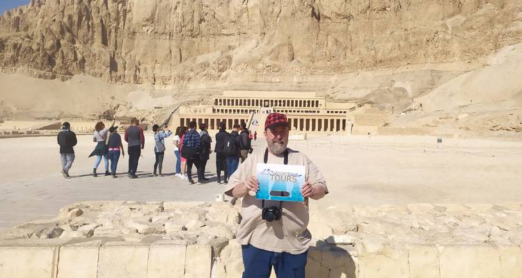 Een persoon die een toeristenbord vasthoudt voor de Hatshepsut-tempel.
