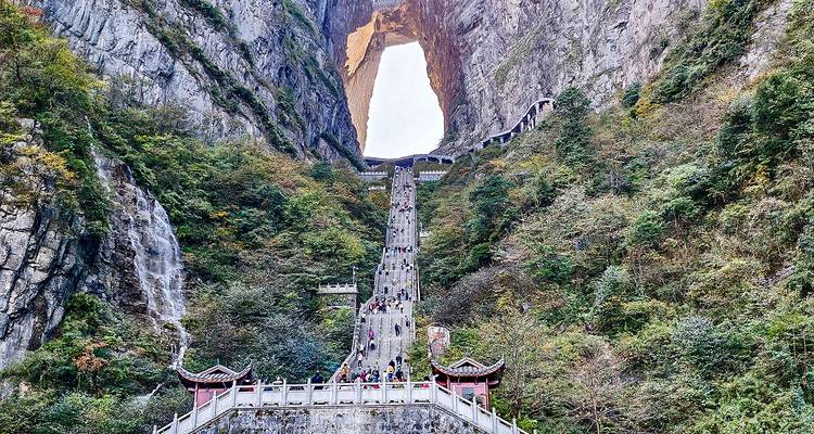 Touristen, die eine lange Treppe hinaufsteigen, die zu einem großen natürlichen Felsbogen führt.
