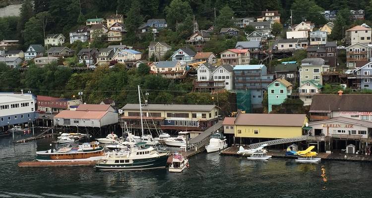 Charming hillside town with colourful wooden houses overlooking a marina dotted with small boats.