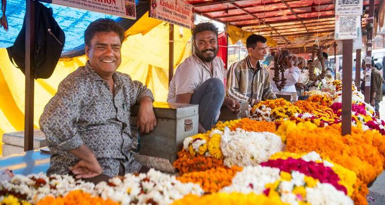 Des hommes vendant des fleurs à un étal de marché.