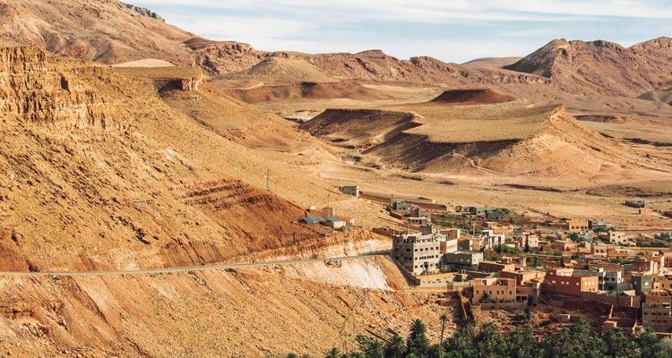 Paysage désertique avec une route sinueuse et un petit village.