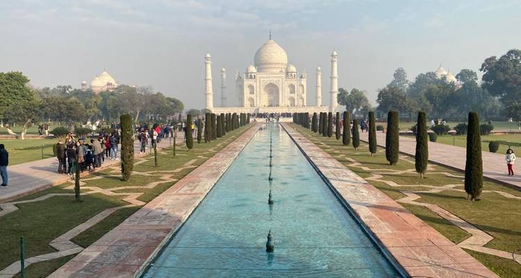 Iconische aanzicht van de Taj Mahal met reflecterende vijver en bezoekers.