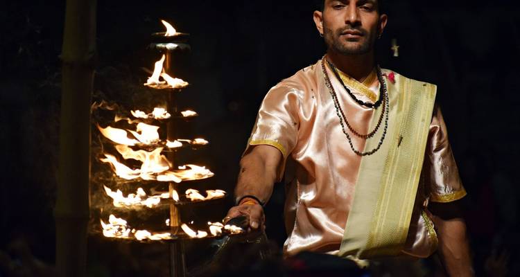 Een man die een lamp met meerdere vlammen vasthoudt, mogelijk tijdens een culturele ceremonie.