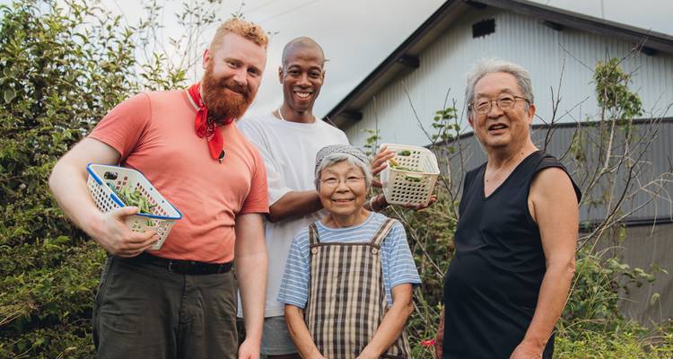 Group of people posing for a photo outside with vegetation in the background.