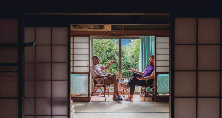 Dos personas sentadas hablando dentro de una habitación tradicional japonesa.