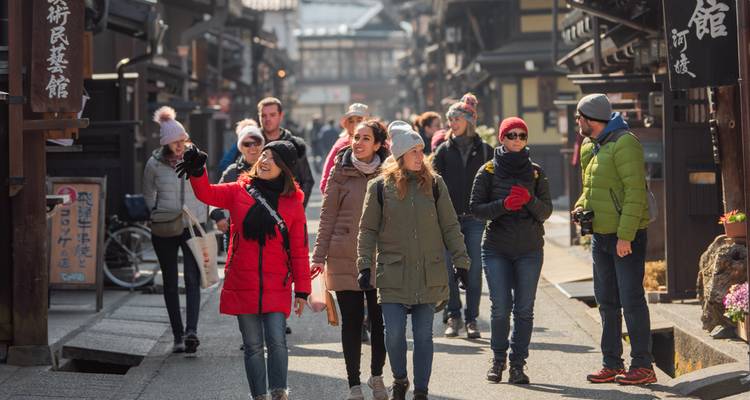 Grupo de turistas caminando por una calle tradicional japonesa.