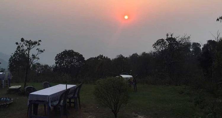 Sunset over a garden area with tables and chairs.