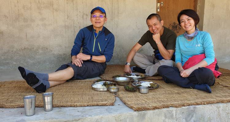 Three people sitting together, dining with traditional dishes.