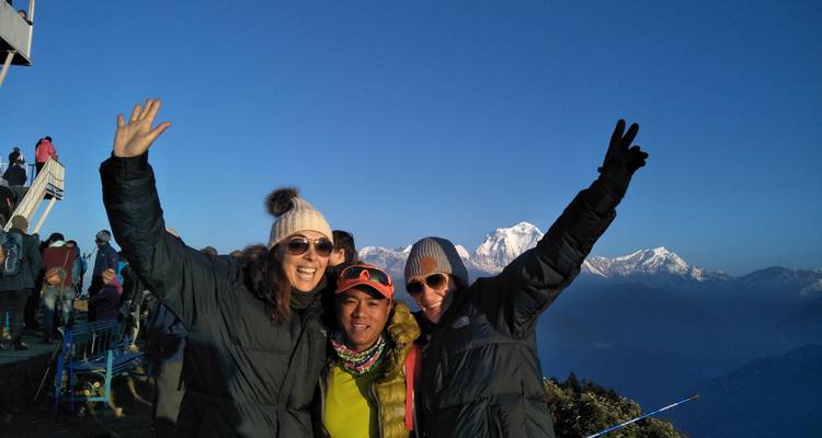 Three people posing with mountainous background.