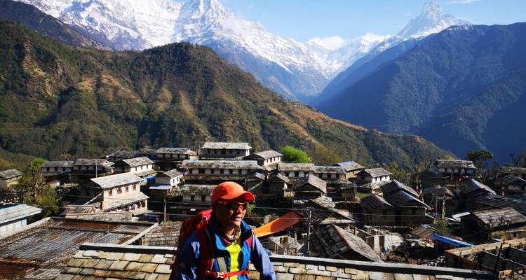 Person in hiking gear with village and mountains behind.