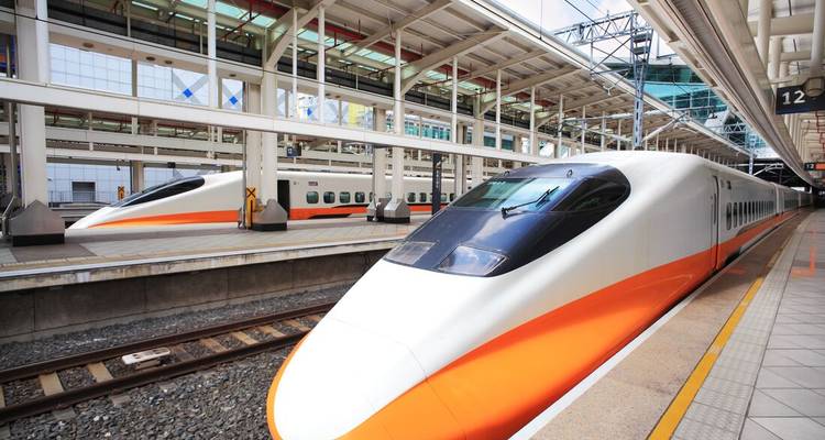 Dos elegantes trenes bala Shinkansen esperando en la plataforma de una estación moderna.