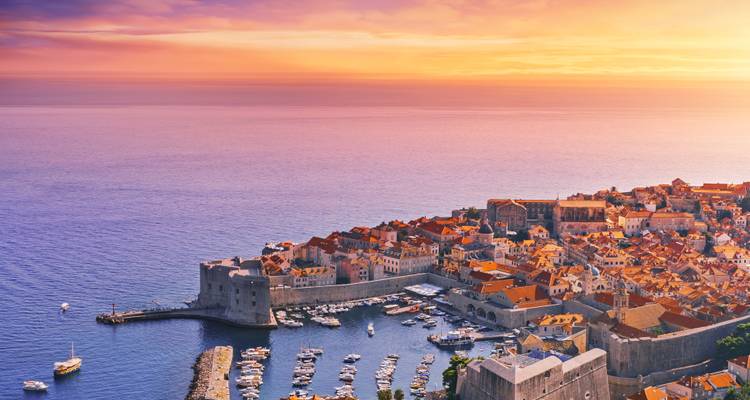 Gouden zonsondergang over de ommuurde oude stad van Dubrovnik en de haven die in de Adriatische Zee uitsteekt.