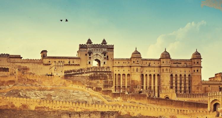 Amber Fort under a blue sky with birds flying.