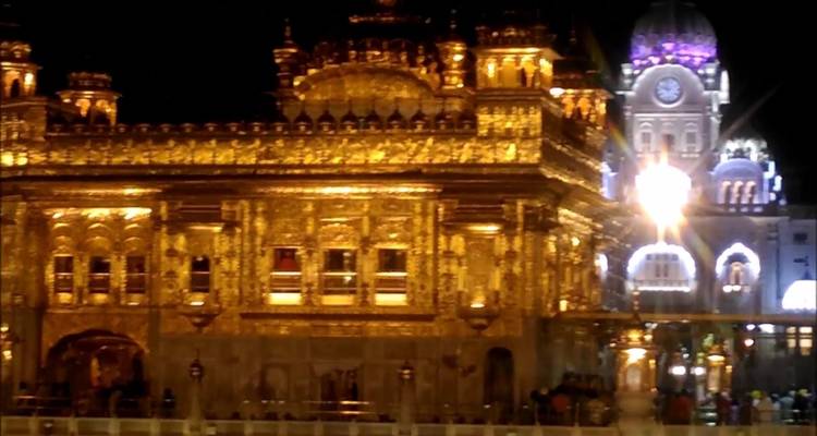 Ein nächtlicher Blick auf einen goldenen Tempel, der mit lebendigen Lichtern beleuchtet ist.