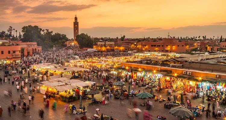 Place Jemaa el-Fnaa, place de marché animée au coucher du soleil avec de nombreux visiteurs.