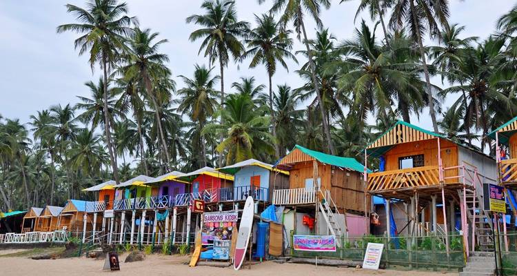 Bunte Strandhütten entlang eines palmengesäumten Strandes in Goa.