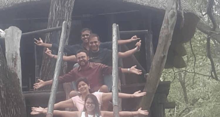 Grupo de personas posando en una estructura de madera con los brazos extendidos.