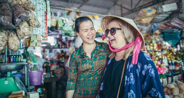 Dos mujeres disfrutando y riendo en un mercado vibrante.