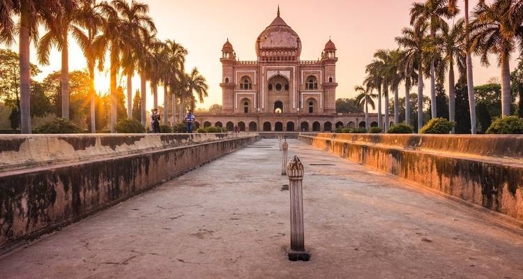 Tomb building amid palm trees with the sun setting.