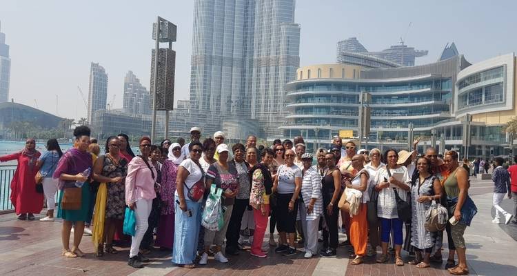 Gruppe von Menschen, die vor einer Stadtsilhouette mit moderner Architektur posieren.